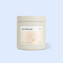 TUSHY Late Bloomer jar candle on a light blue background