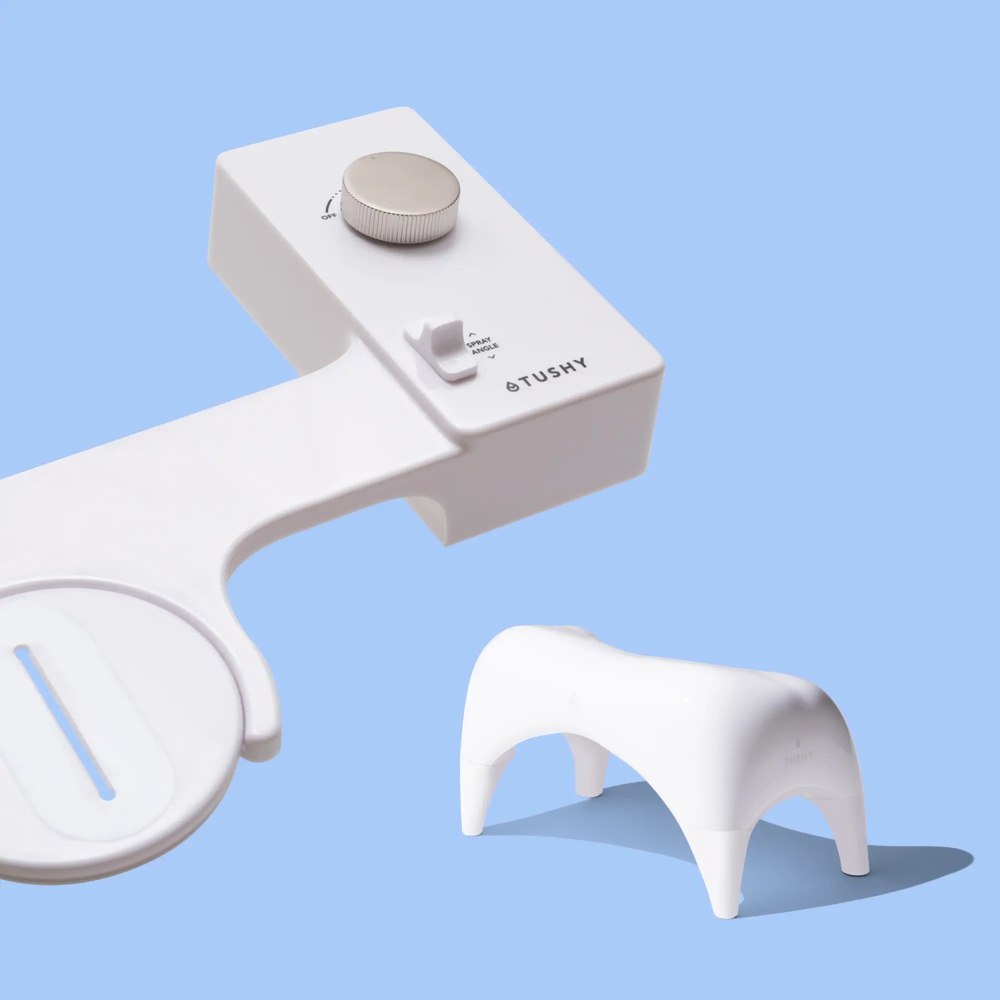White TUSHY Classic console with a platinum knob, and a white ottoman on a blue background