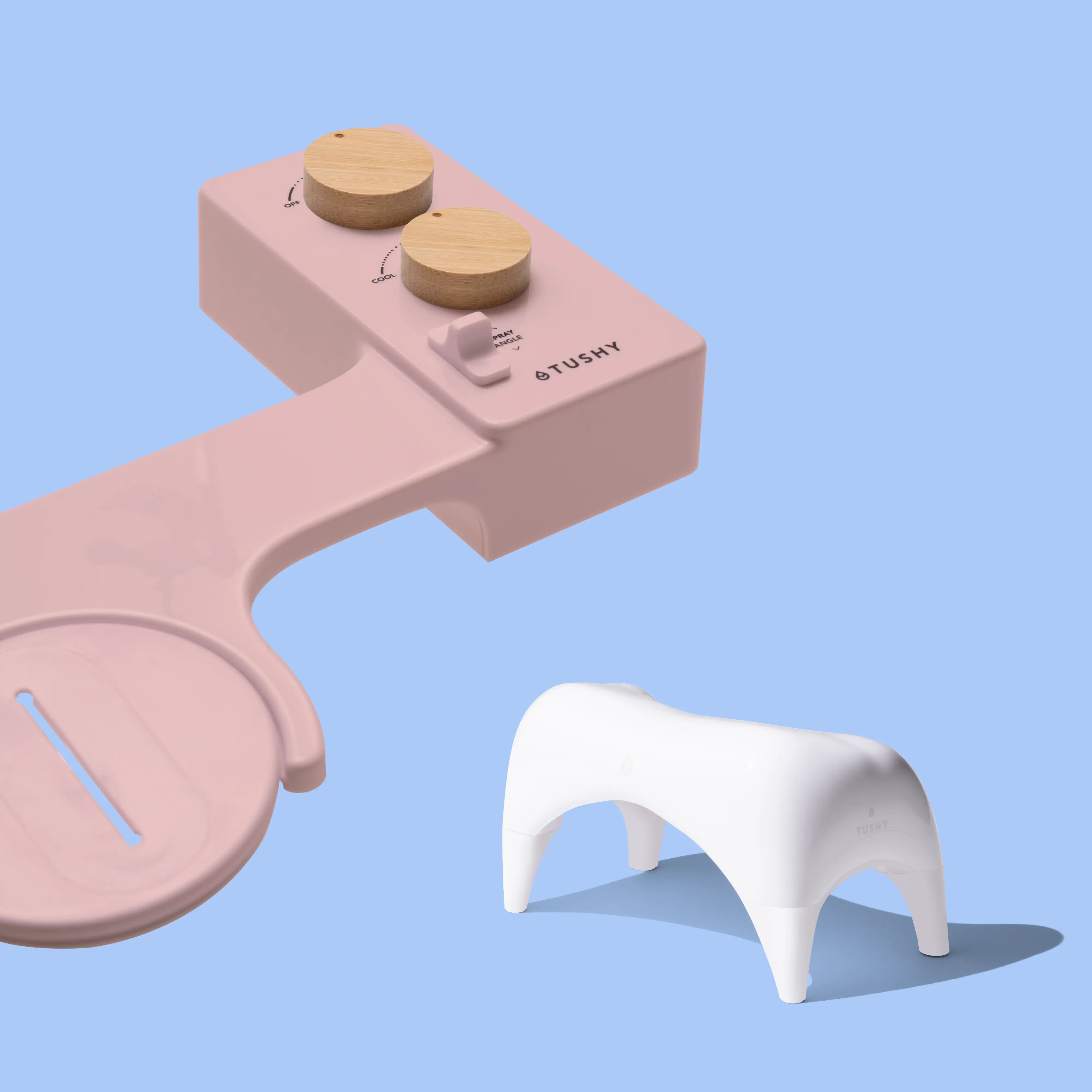 Pink TUSHY Spa console with 2 bamboo knobs, and a white ottoman, on a blue background