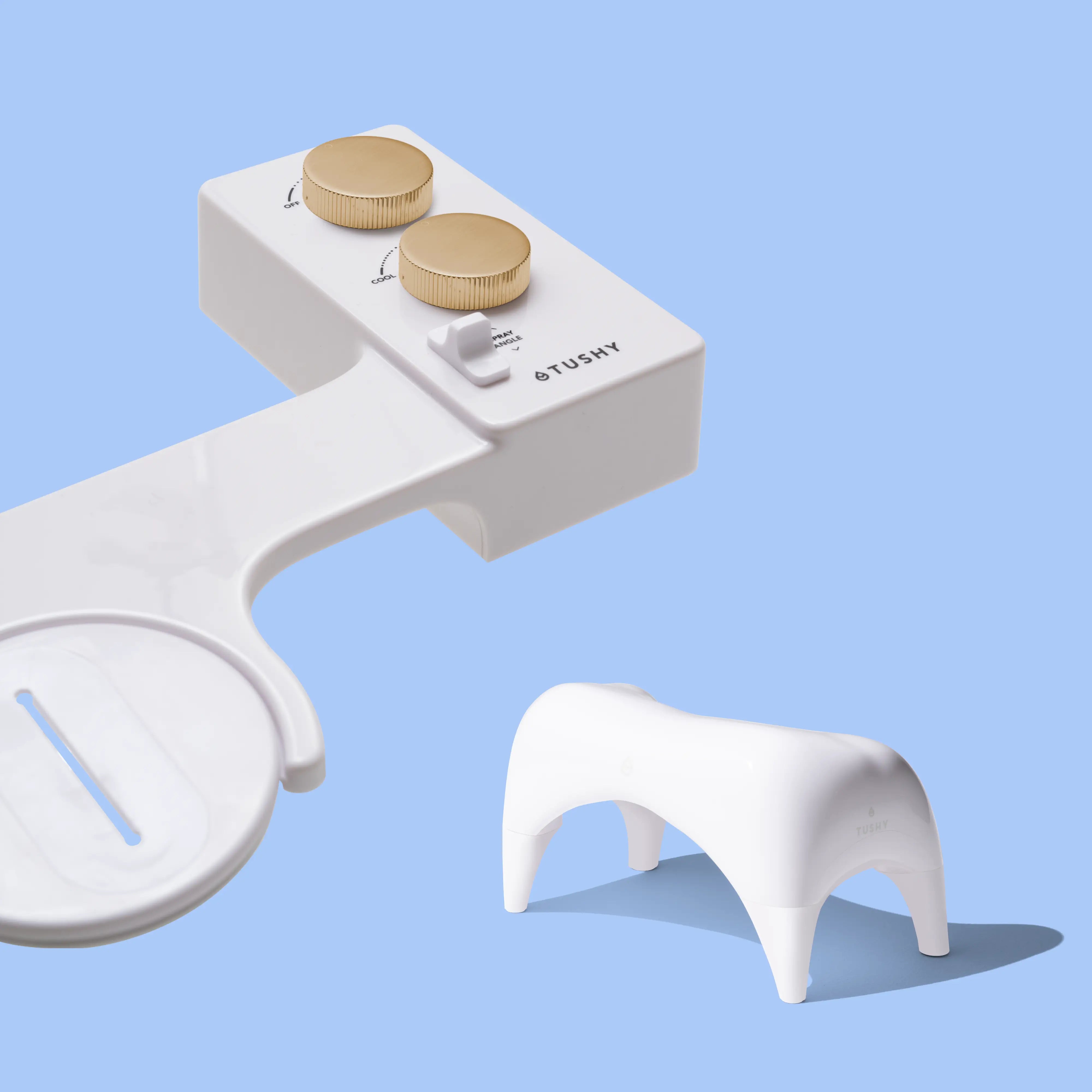 White TUSHY Spa console with 2 gold knobs, and a white ottoman, on a blue background