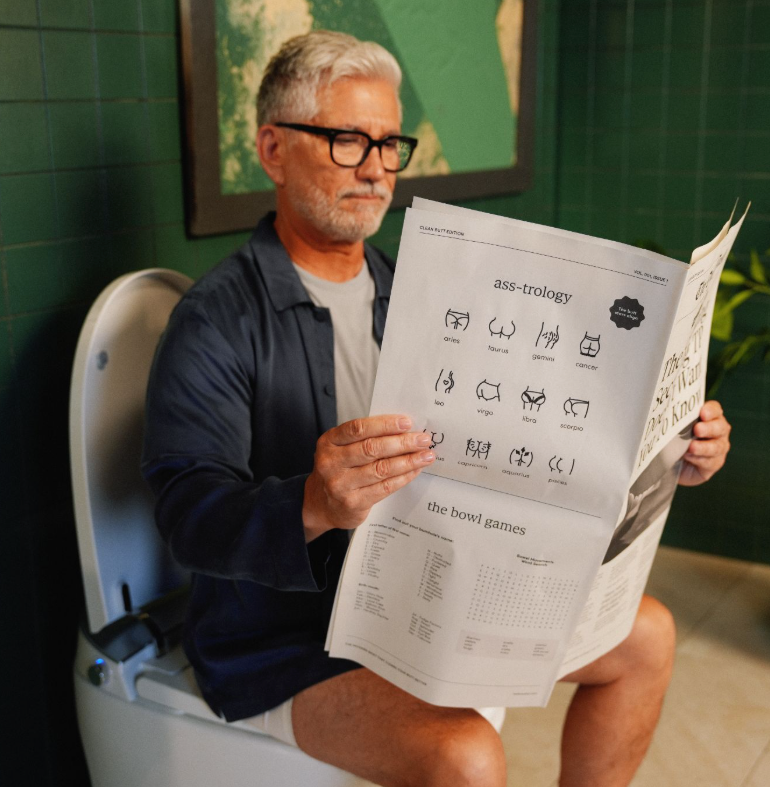 Person reading on a toilet with a TUSHY Classic bidet
