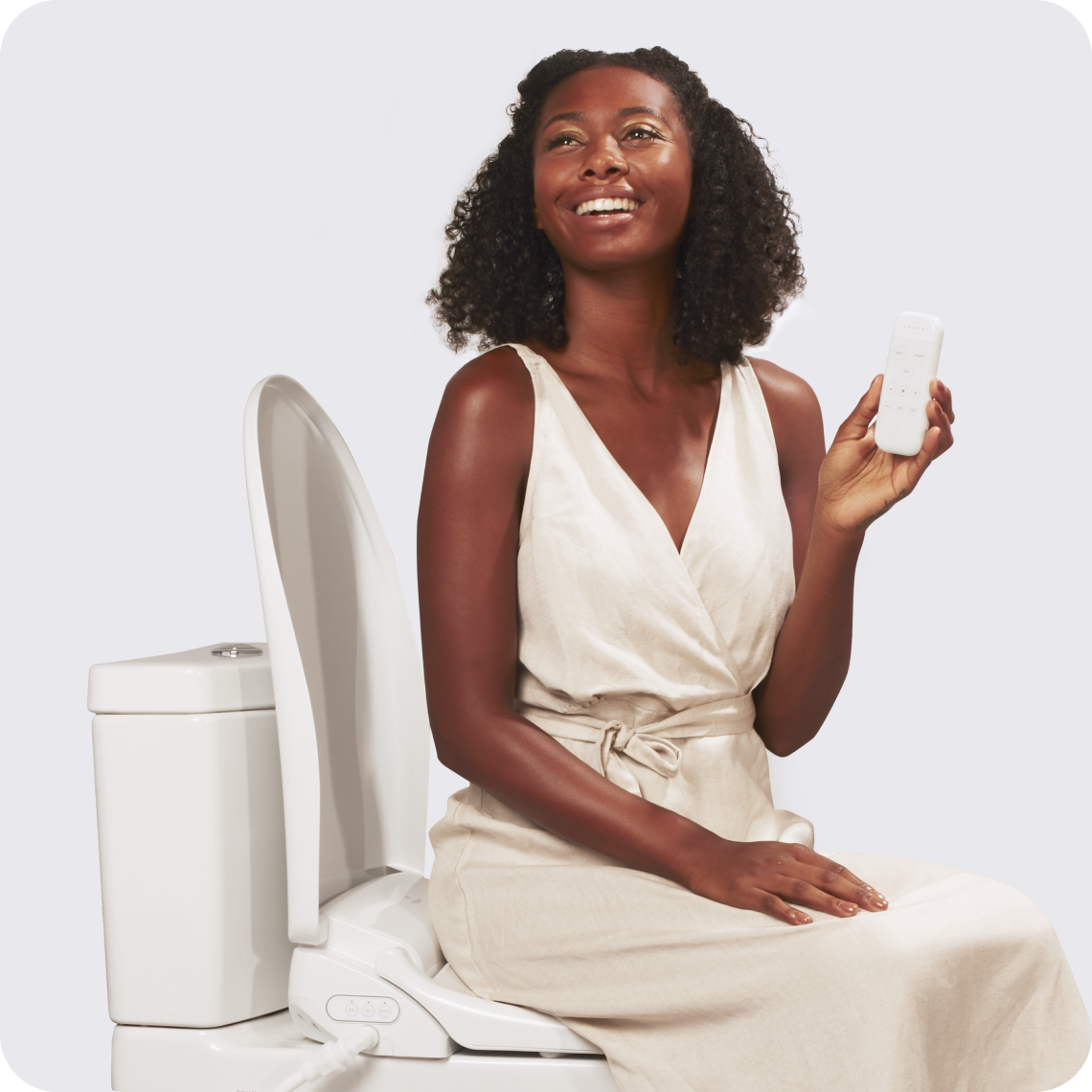 A smiling woman sitting on a toilet with TUSHY Ace Electric Bidet Seat, holding the remote in her hand