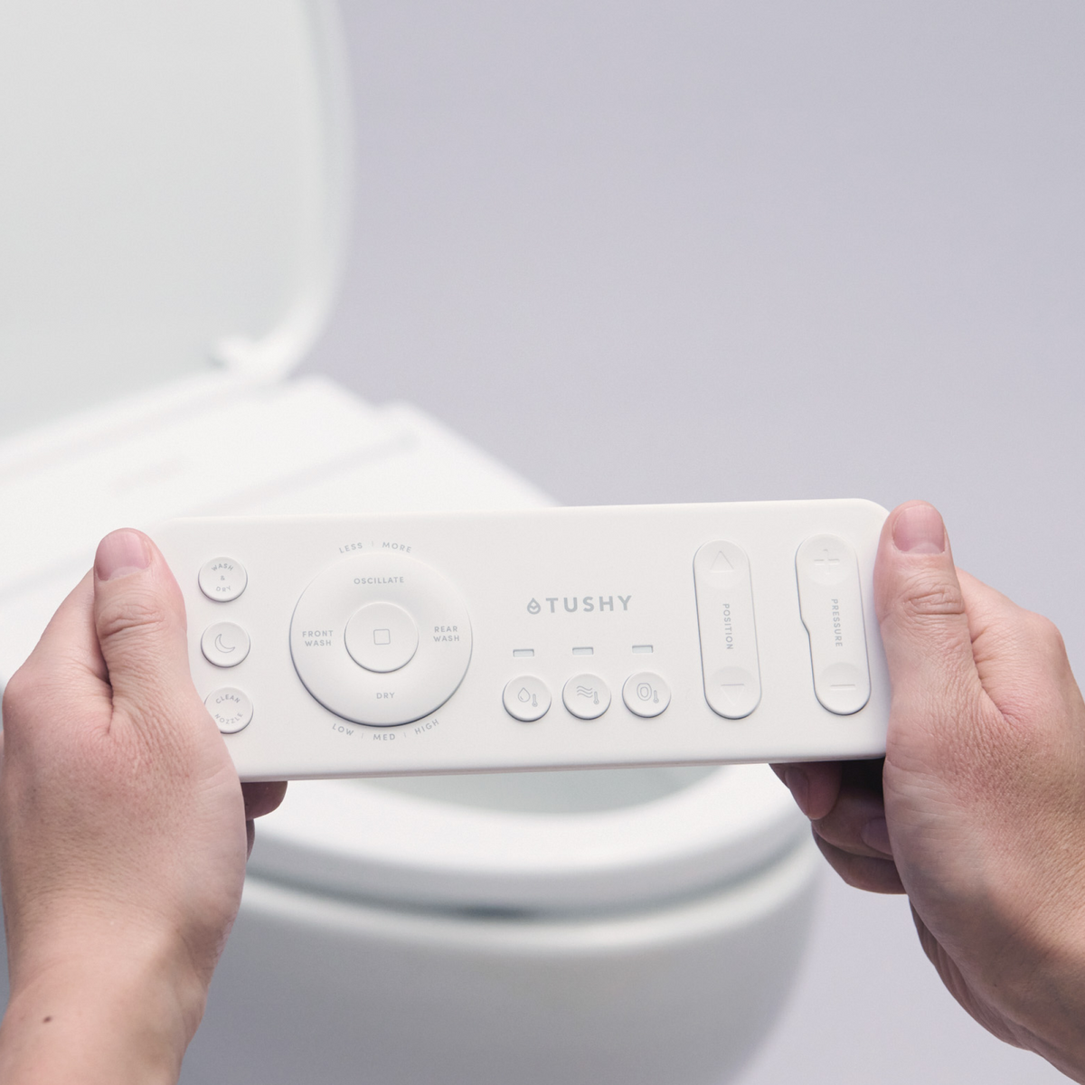 Close up of hands holding a remote for a TUSHY Cloud+
