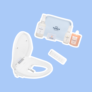 White bidet attachment with remote control, accompanied by personal care products and a candle on a light blue background.