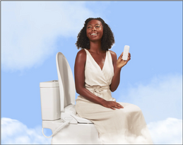 Angelic looking woman sitting on a toilet with a TUSHY bidet toilet seat, holding the remote