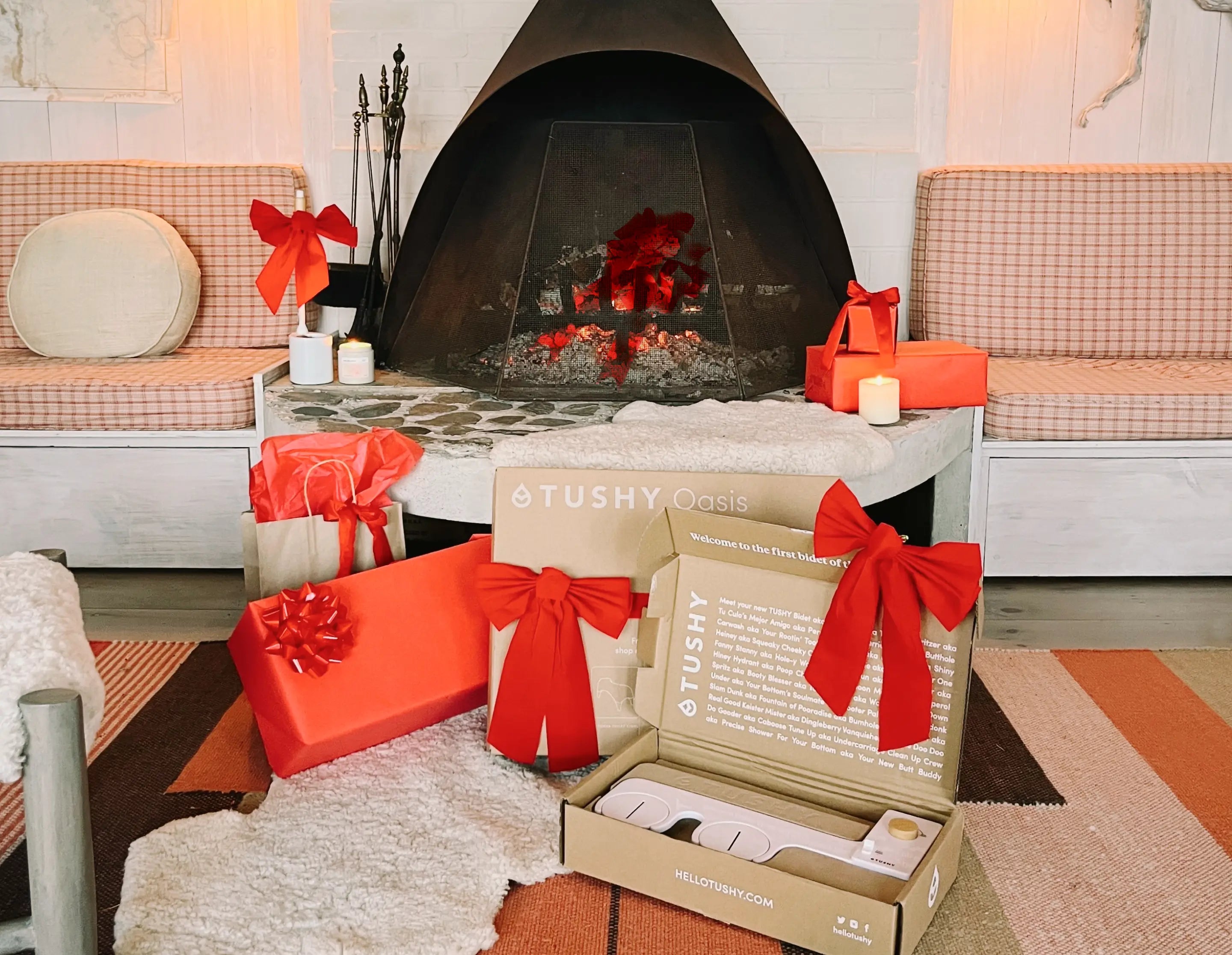 Tushy Gifts with red bows on a rug in front of a fireplace.