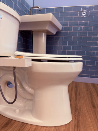 Toilet with a white seat and tank, set against blue tiled wall and wooden floor.