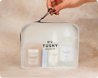 Clear zippered pouch containing three products: a candle and two bottles labeled "Evening Wood," "Morning Zen," and "Afternoo