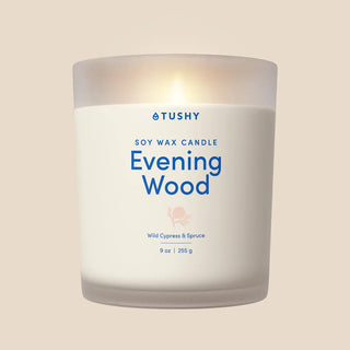 Soy wax candle in a frosted glass container labeled "Evening Wood" with notes of wild cypress and spruce.