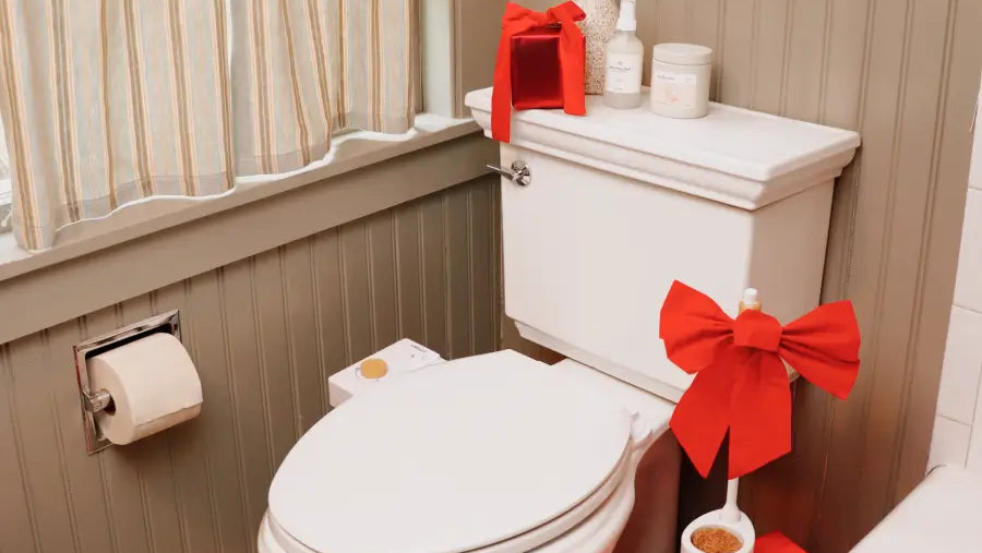 Bathroom with a toilet decorated with red bows and toiletries on the tank.