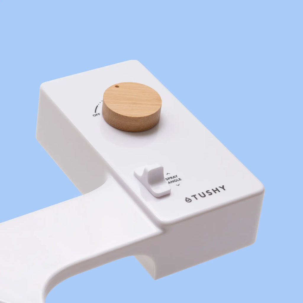 White 'TUSHY' Classic console, with a bamboo pressure control knob, on a light blue background
