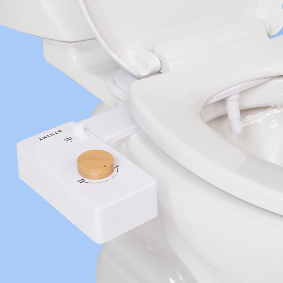 White 'TUSHY' Classic console, with a bamboo pressure control knob, installed on a toilet, on a light blue background