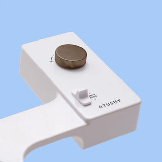 White 'TUSHY' Classic console, with a bronze pressure control knob, on a light blue background