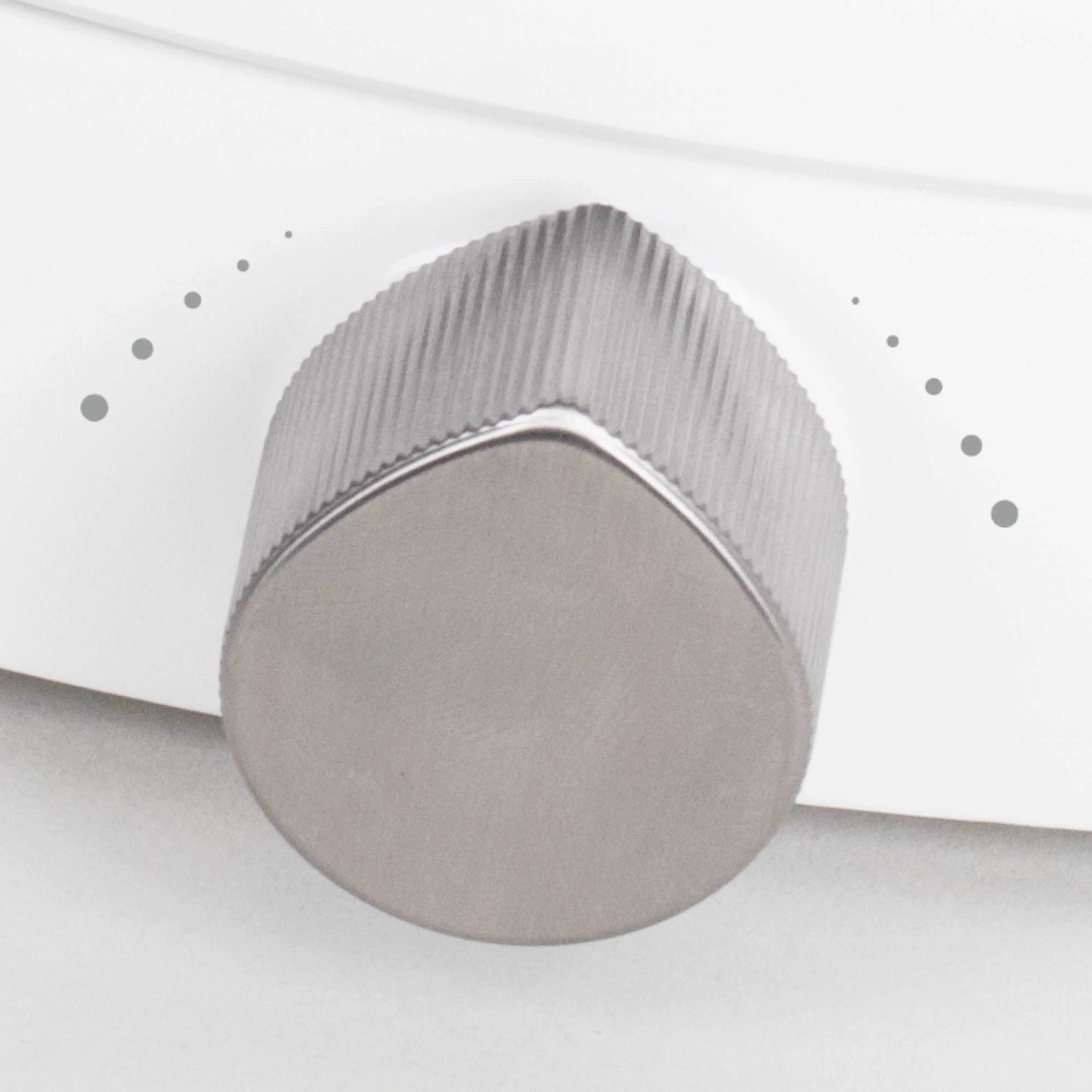 Close-up of a TUSHY Oasis platinum control knob on a white background