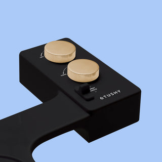 Black TUSHY Spa console with 2 gold knobs, on a blue background