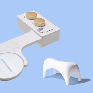 White TUSHY Spa console with 2 gold knobs, and a white ottoman, on a blue background