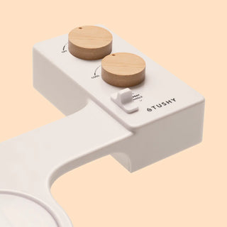 Control panel with two wooden knobs and a switch for adjusting spray angle on a white device.