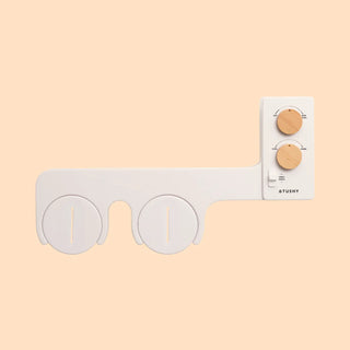 Bidet attachment with two circular nozzles and control panel featuring three knobs for water pressure and temperature.