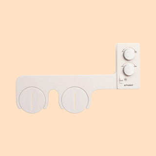 White bidet attachment with two circular nozzles and three control knobs on the side.