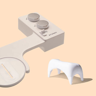 White bidet attachment with two control knobs and a small white stool.