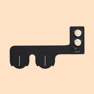 Black bidet attachment with two circular controls and a vertical panel featuring additional knobs.