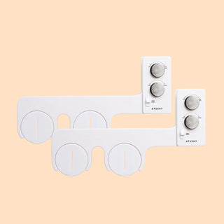 White bidet attachment with control knobs for water pressure and temperature adjustments.
