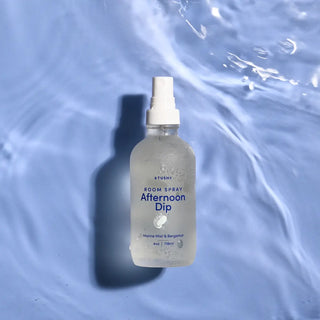 A bottle of Afternoon Dip Room Spray on a watery background