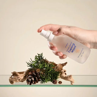A hand spritzing Evening Wood room spray