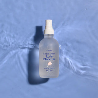 A bottle of late bloomer room spray on a watery background