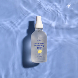a bottle of Morning Zest Room Spray on a watery background