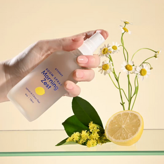 A hand spritzing Morning Zest room spray