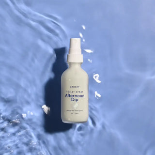 A bottle of Afternoon Dip toilet spray on watery background
