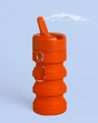 Collapsible orange travel bidet with a spray nozzle and a carabiner for easy attachment.