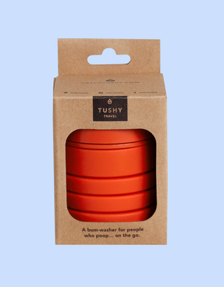 Compact orange travel bum-washer in a cardboard package with a handle and product description on the front.