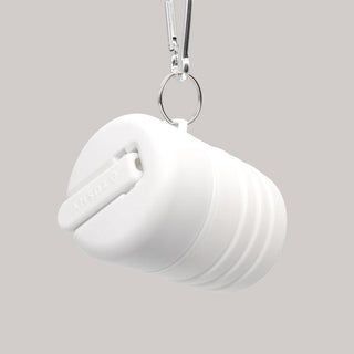 Compact white travel container with a keyring attachment and a sliding lid.