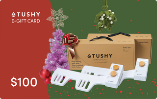 E-gift card for TUSHY products, featuring a $100 value with decorative elements like a purple tree and festive accents.